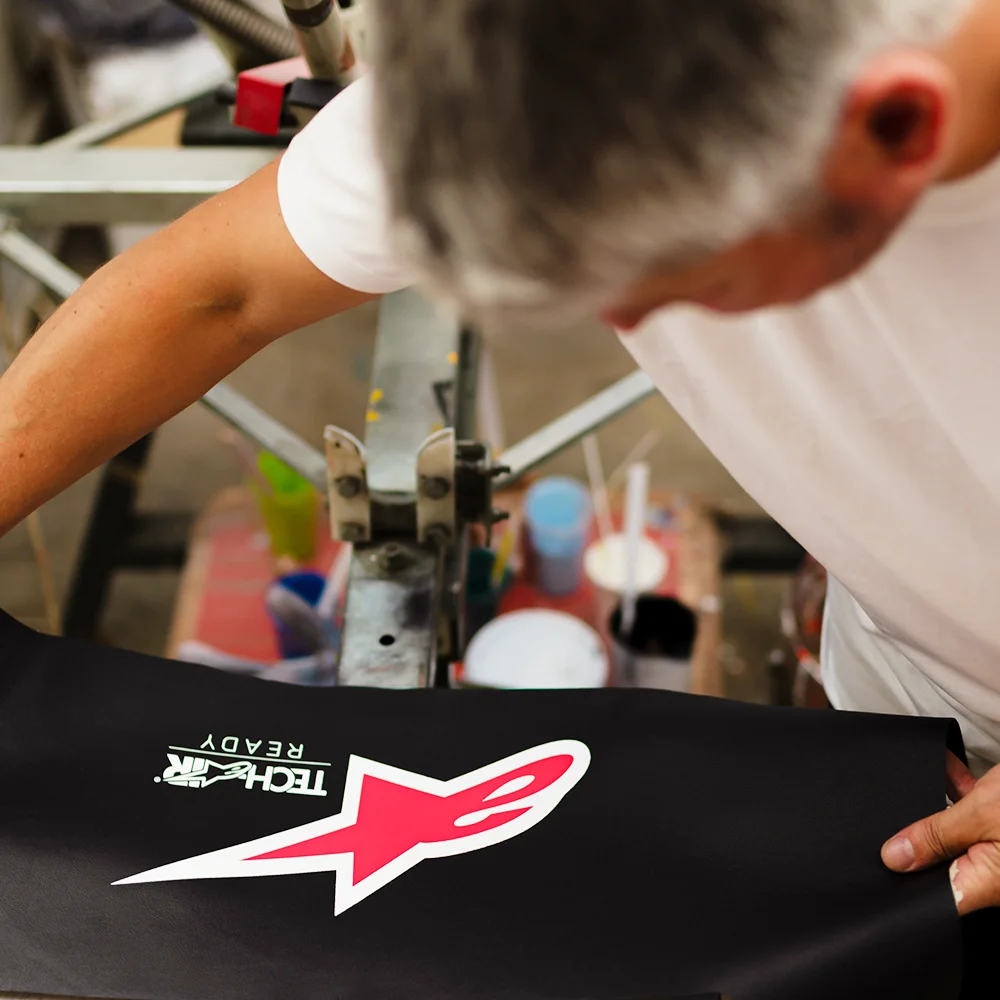 Operator verificând manual material serigrafiat logo Alpinestars - Antel Print